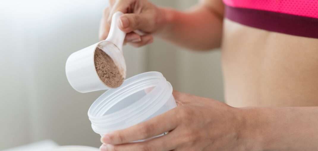 woman pouring powered supplement into container