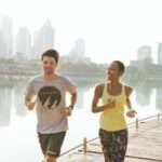 man and woman jogging alongside waterfront in city