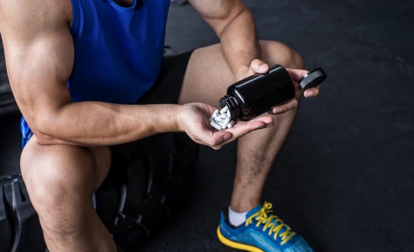 A man pouring prohormone pills into his hand at the gym