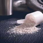 Adaptogen-based supplement powder in scoop with weights in the background